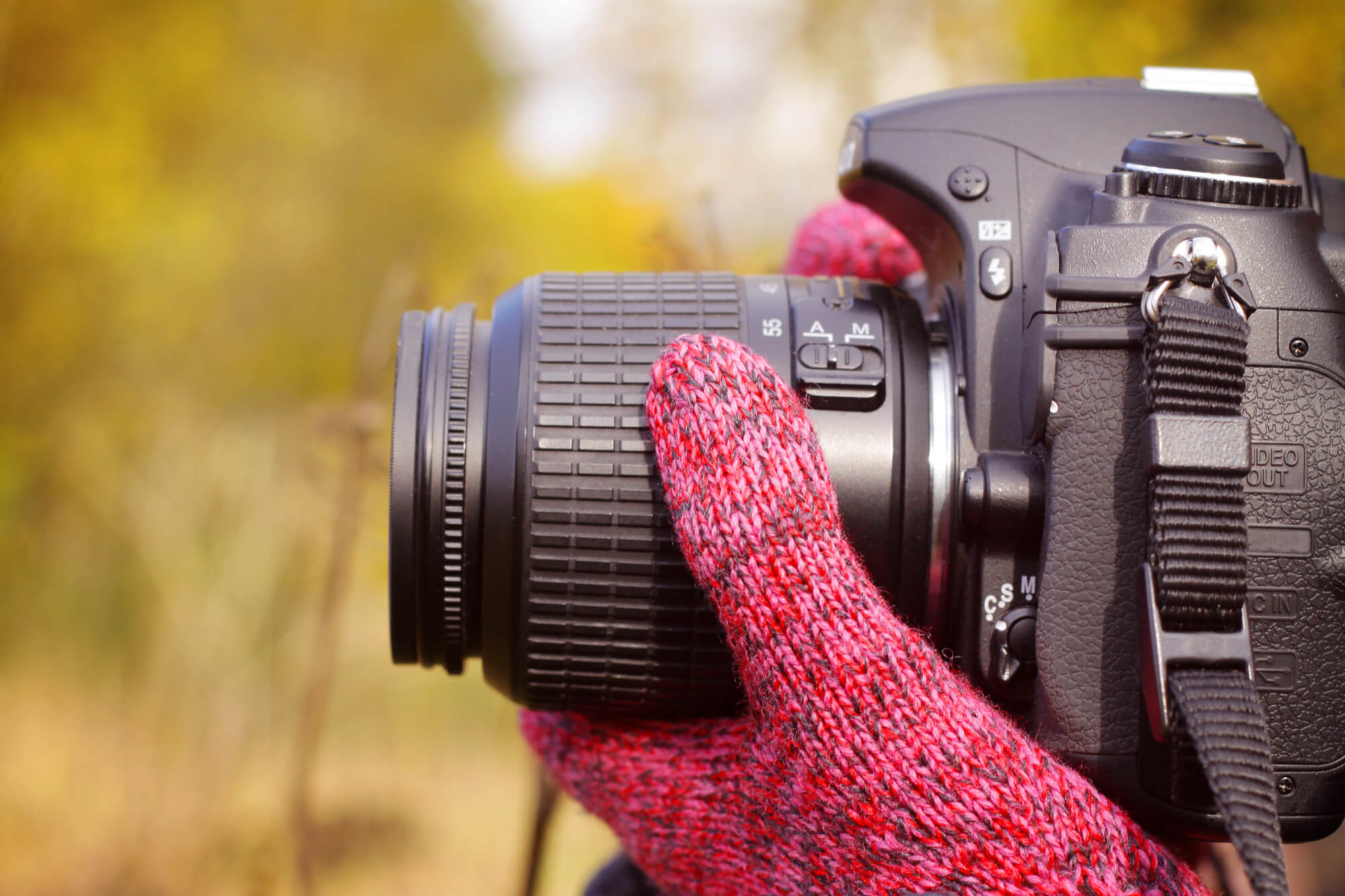 man with red gloves holding a black camera lense